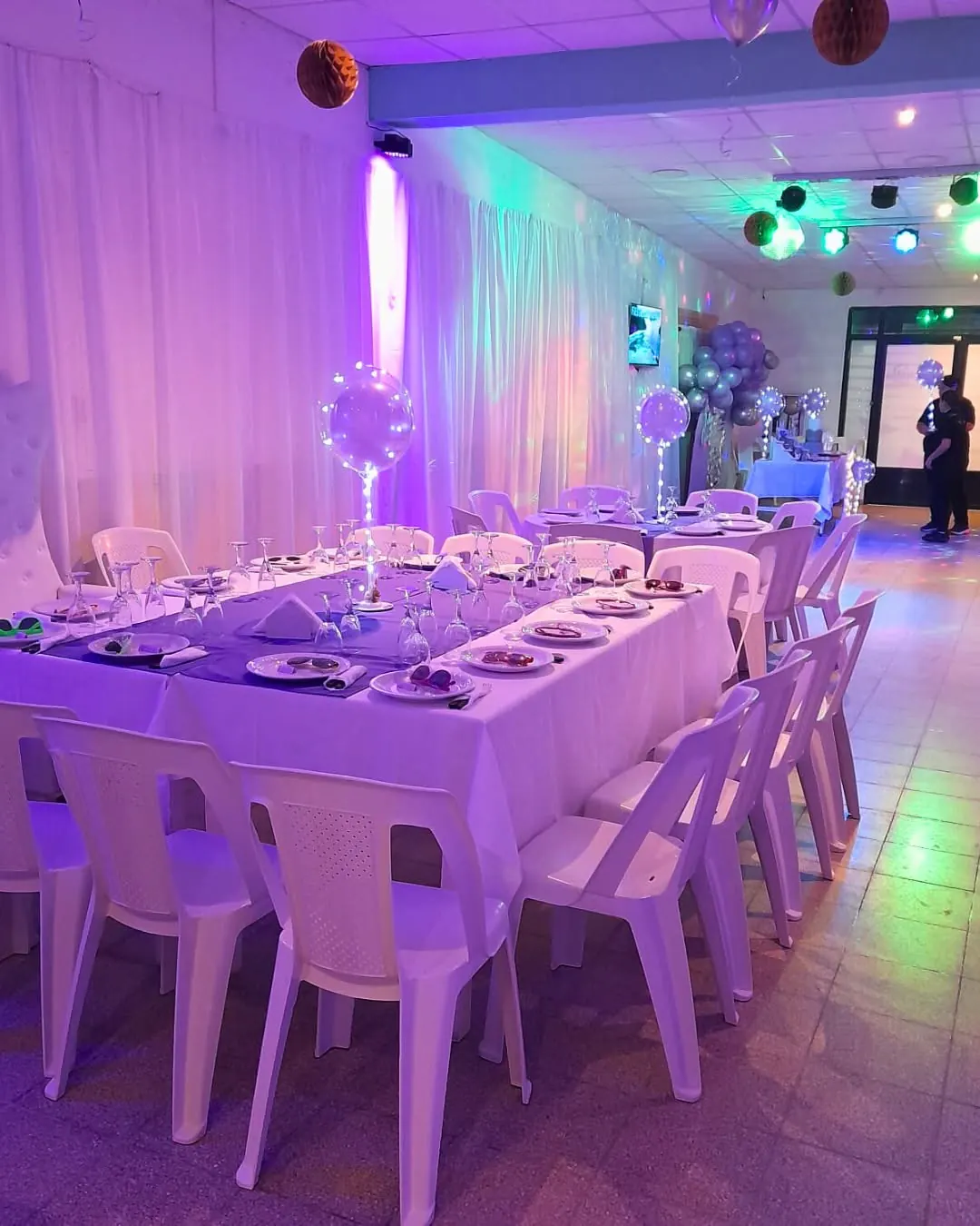 Salón con mesas e iluminación lila para fiesta de 15 años en Utopía